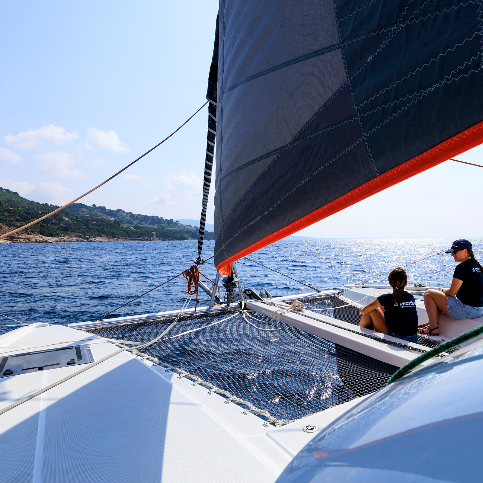 Deux jeunes filles sur les filets d'un catamaran en mer