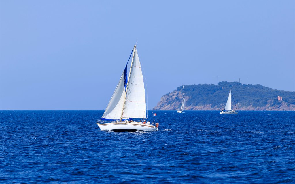 Voilier monocoque à voiles blanches navigant sur l'eau dans la rade de Toulon