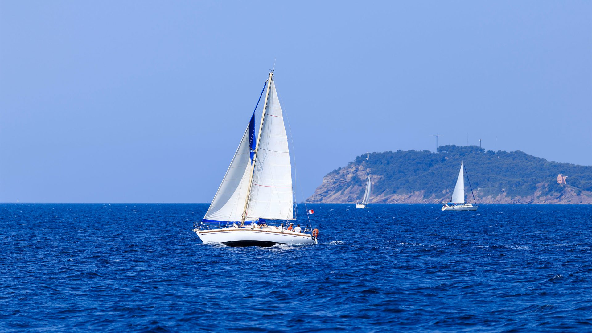 Voilier monocoque à voiles blanches navigant sur l'eau dans la rade de Toulon